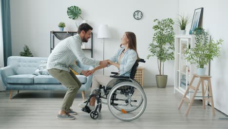 slow motion of young disabled woman in wheelchair and joyful husband dancing having fun at home