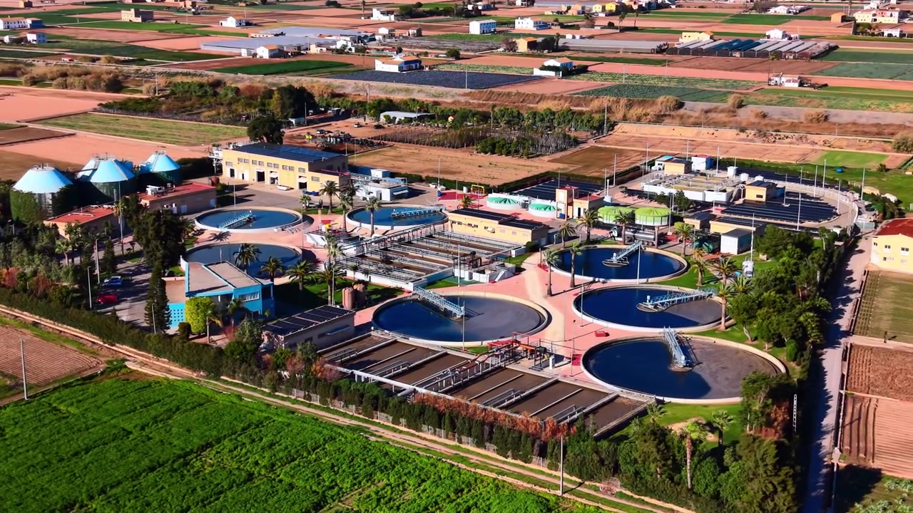 Environmental infrastructure with water purification tanks and large photovoltaic arrays in a rural setting. Solar powered sewage treatment plant with circular clarifiers.