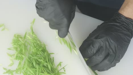 el cocinero corta las cebollas verdes con un cuchillo.