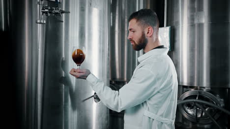 trabajador de una cervecería inspeccionando un vaso de cerveza
