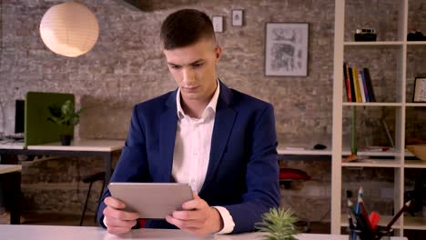 young sweet businessman is watching in tablet, watching at camera, communication concept, business concept