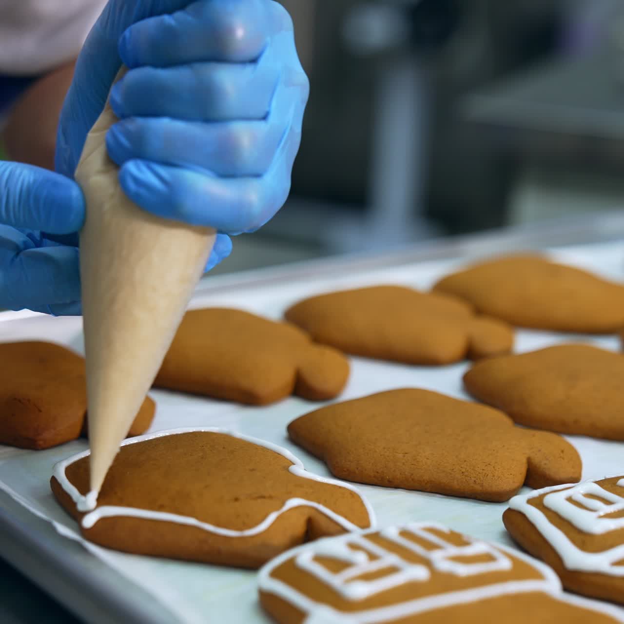 Decorating freshly-baked cookies with white cream. Confectioner squeezes icing from a pastry bag on the gingerbread cake. Close up