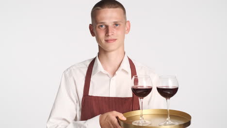 happy waiter serving two glasses of red wine