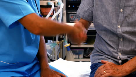 una mujer médico estrechando la mano de un paciente.