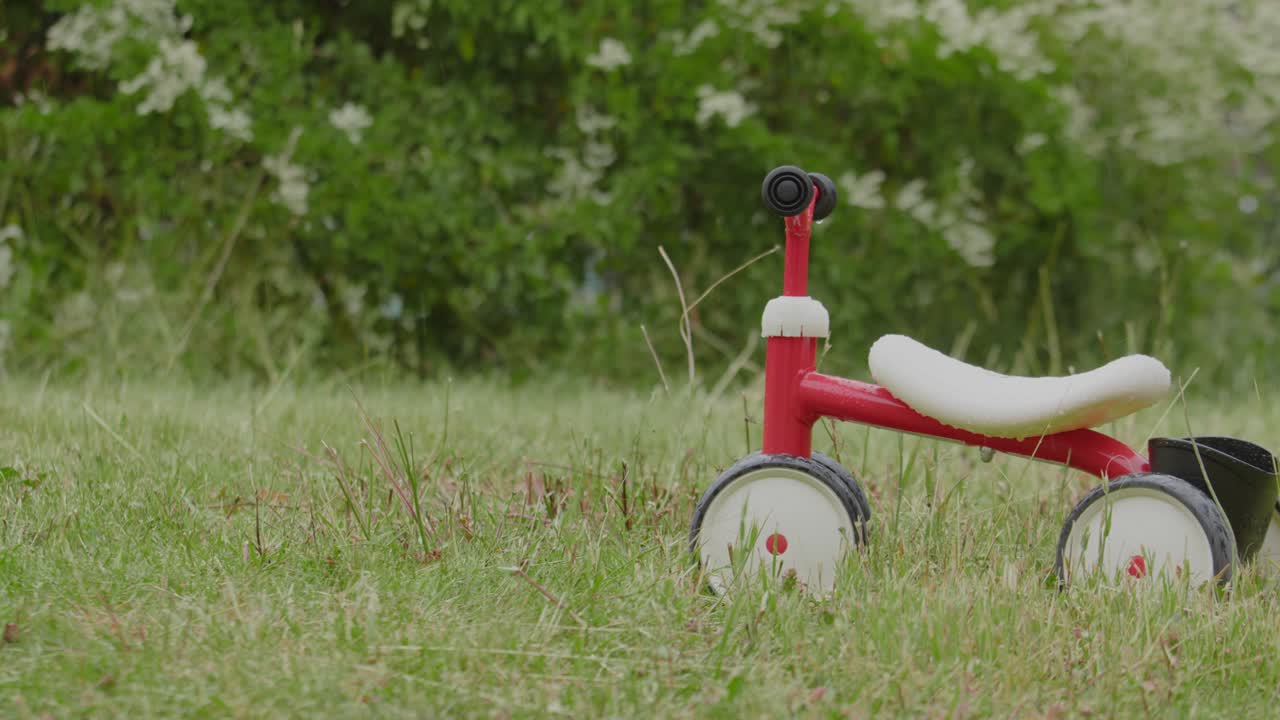 Small Bike, Smoby Rookie Ride On A Wet Lawn During Sunrise. Close-up Shot