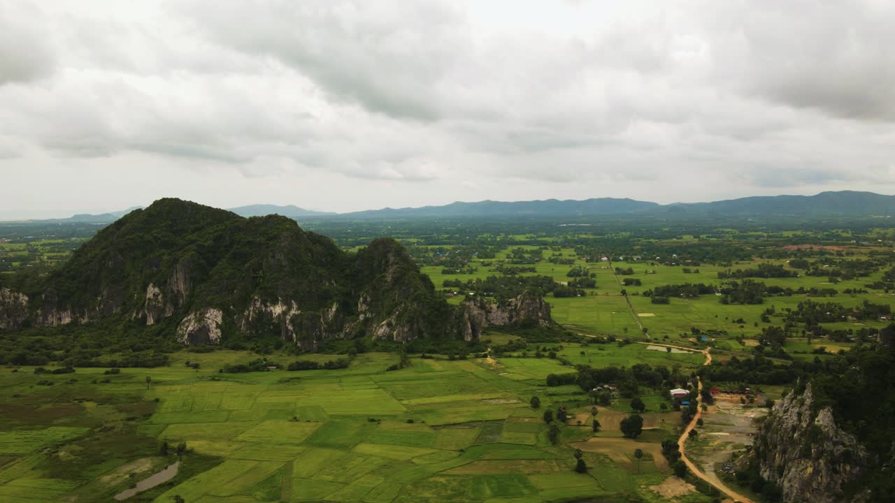 Limestone formations on ripe green rice paddies, flat lands of Southeast Asia