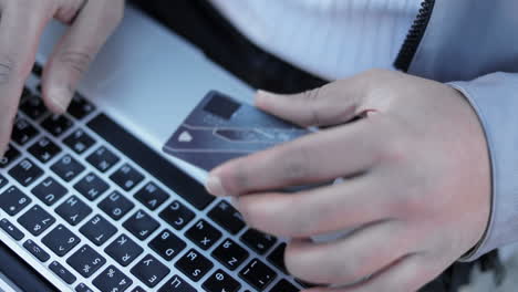 male hands typing card number on keyboard of laptop