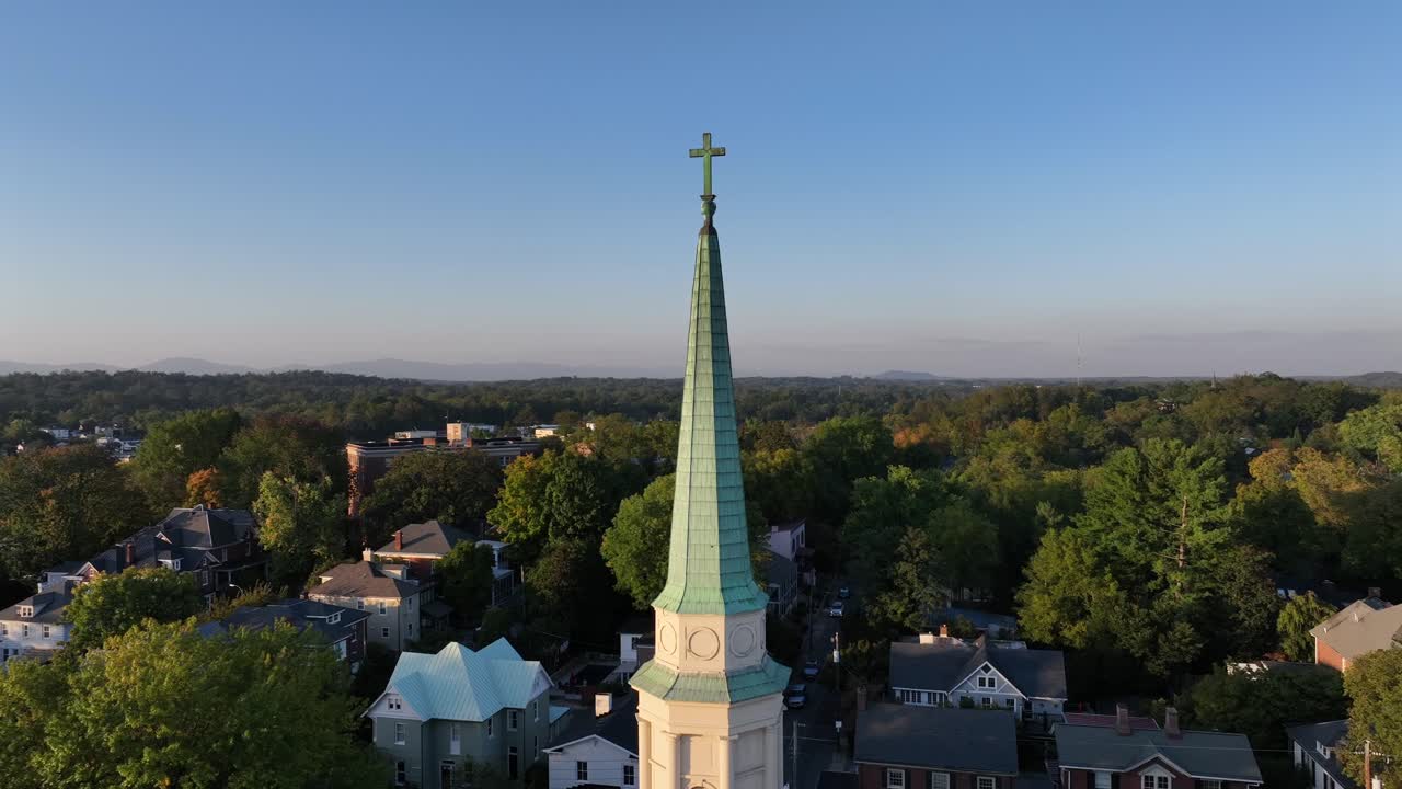 Aerial orbit shot of church tower in american town during sunset time in autumn. colorful trees in american neighborhood. Wide shot.