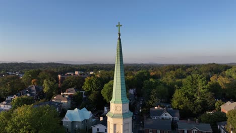 aerial orbit shot of church tower in american town during sunset time in autumn. colorful trees in american neighborhood. wide shot.