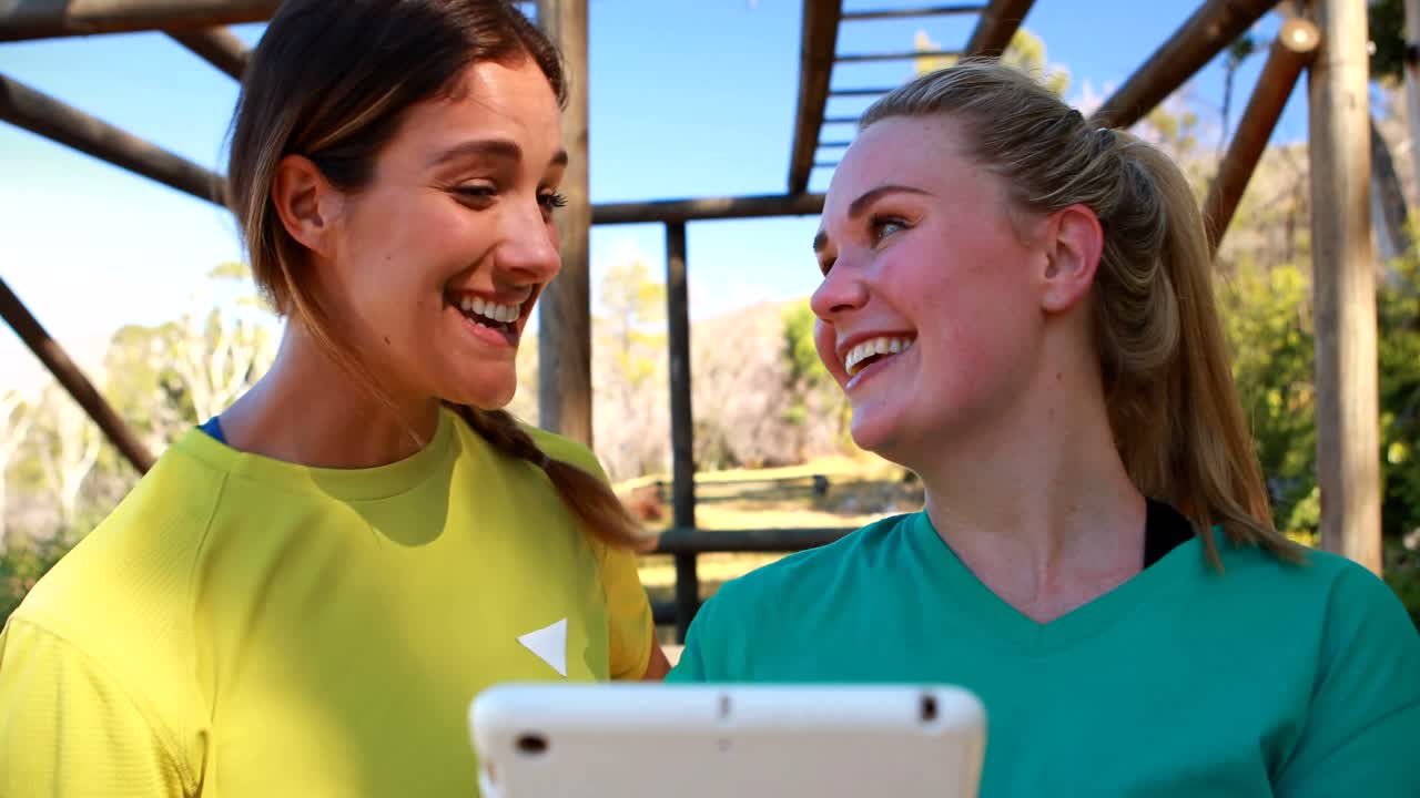 amigos felices usando tableta digital durante una carrera de obstáculos