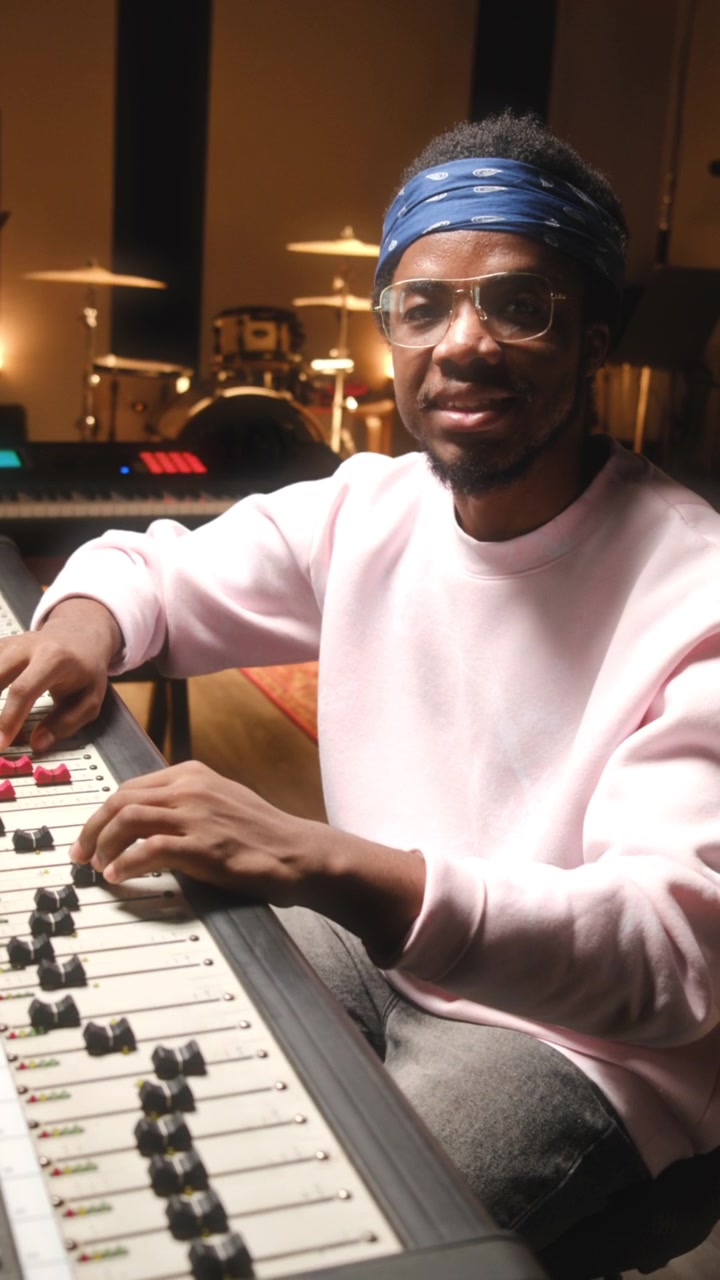Portrait of Cheerful African American Audio Engineer Sitting at Mixing Console