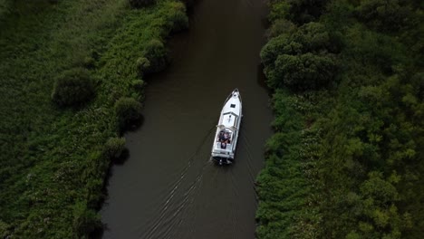 Aerial-Drone-Birdseye-4k-Footage-of-a-Boat-travelling-along-River-Yare,-in-the-rural-Norfolk-Broads-and-surrounding-fields-Norfolk
