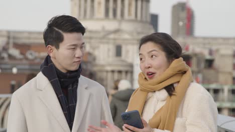 young asian couple on holiday walking across millennium bridge with st pauls cathedral in background 2