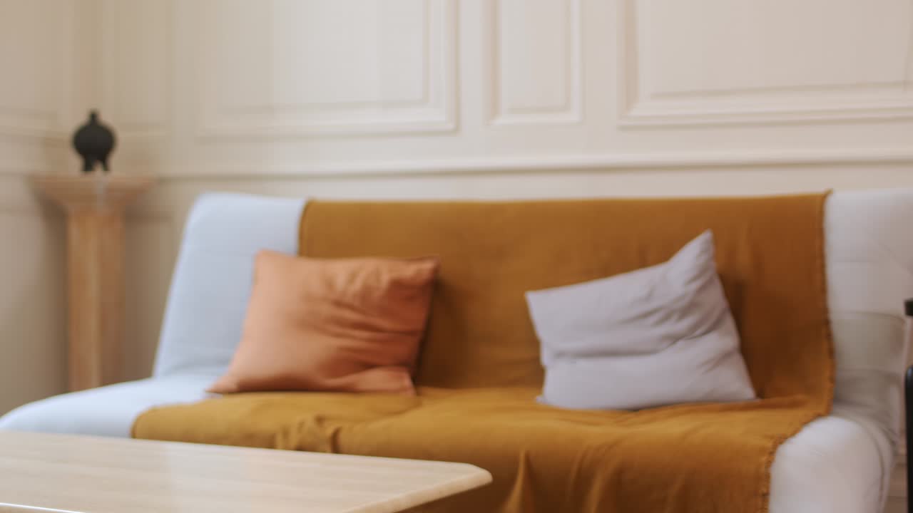 A Woman in a Yellow Knitted Sweater and Jeans Strolls Through the Living Room, Holding a Bottle of Wine - Close Up