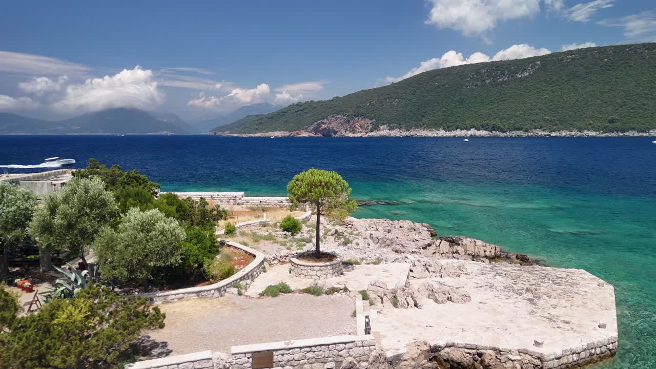 Low aerial approaches fortified building on tiny island in Montenegro