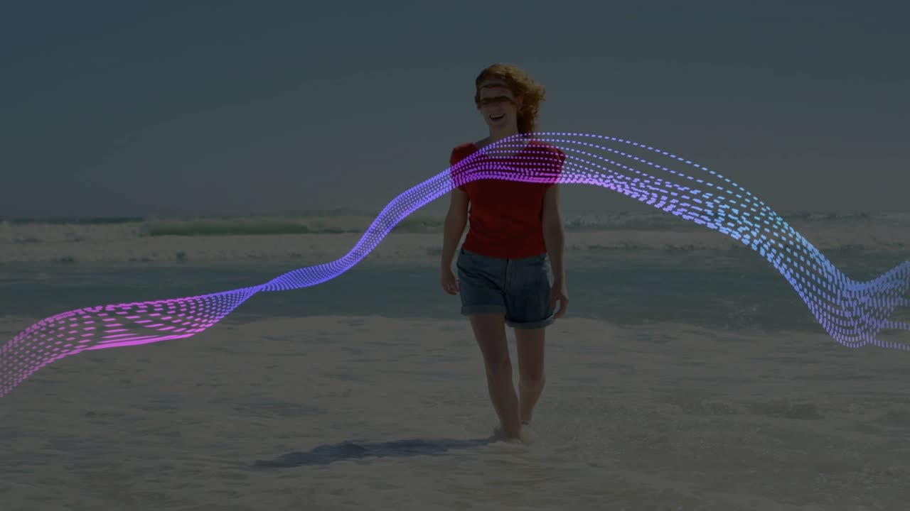 Kvinne går ut i grunt vann og langs strandkanten, et prikket bånd vifter over en form som viser teknologi