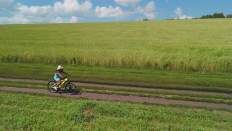 girl cycling through a green field
