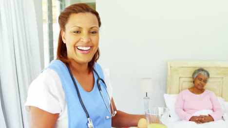 Smiling-female-doctor-serving-breakfast-to-senior-woman-on-bed-4k