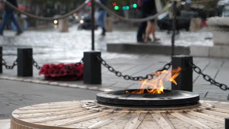 Slow-motion-fire-memorial-burning-on-overcast-moody-day-in-front-of-Arc-De-Triomphe,-Paris,-France