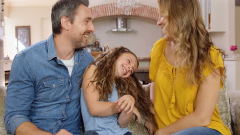 padres hablando con su hija en el sofá