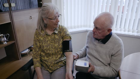 elderly couple checking blood pressure at home