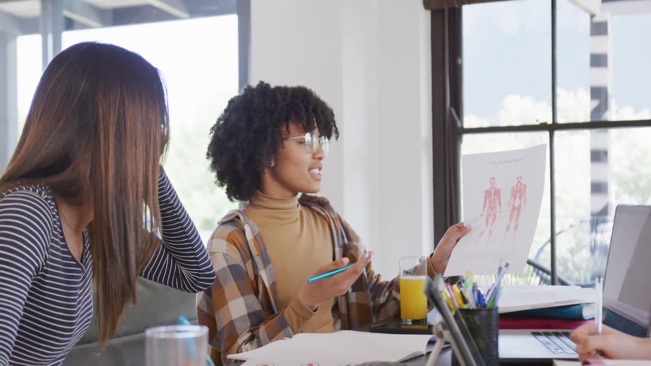 Diverse teenager girls friends using laptop and learning together at home, slow motion