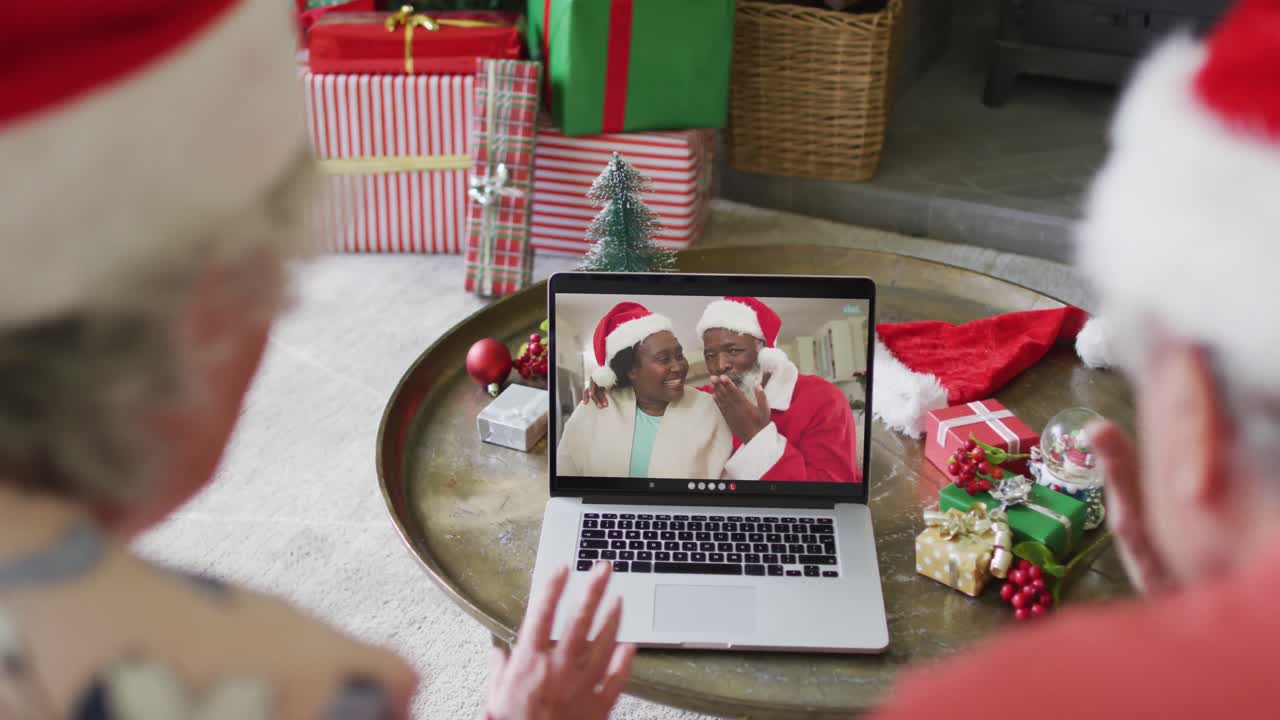 pareja caucásica de alto nivel con sombreros de santa usando una computadora portátil para una videollamada de navidad con pareja en la pantalla