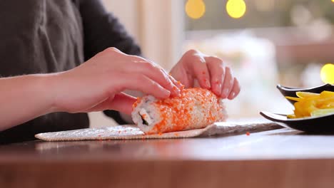 making sushi at home kitchen. woman hands rolling homemade sushi.