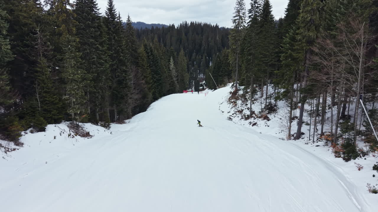 Attività sciistica su un pendio innevato in un'area montana boschiva durante una giornata invernale nuvolosa