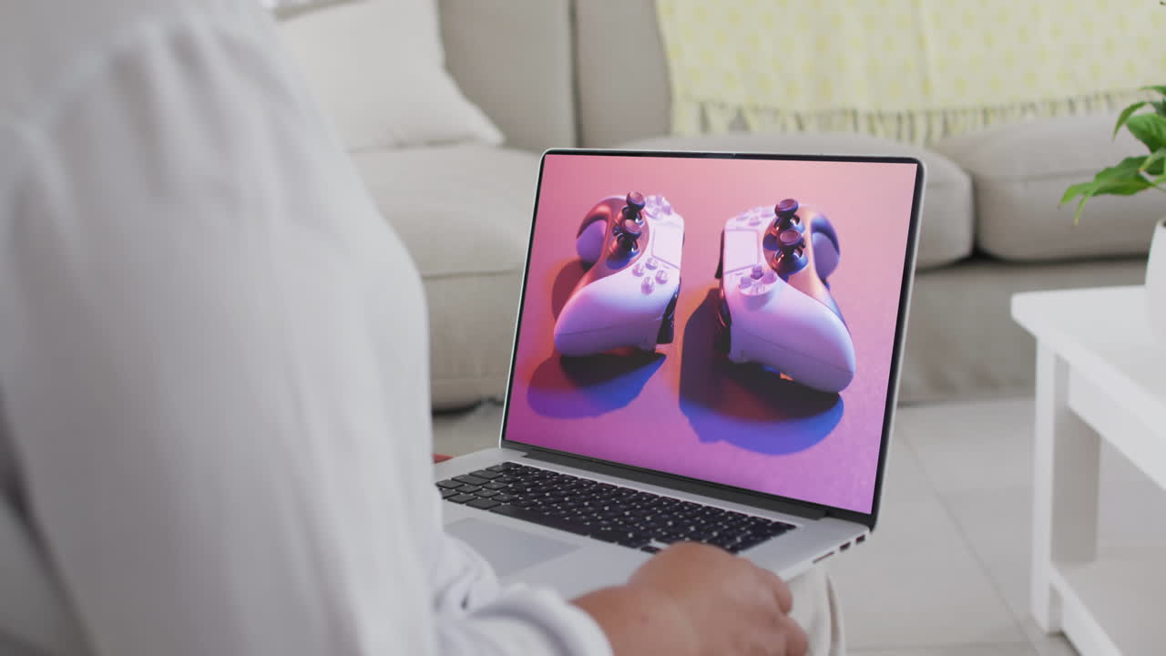 mujer biracial usando portátil en casa compras en línea para gamepads, cámara lenta