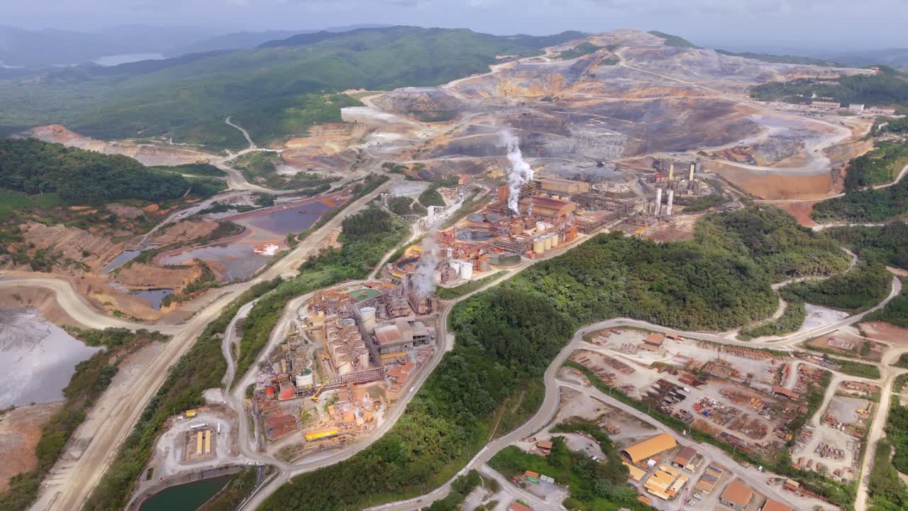 Industrial factory with mining complex and rising steam. Aerial top down shot. Green landscape with mountains in Cotui, Dominican Republic.