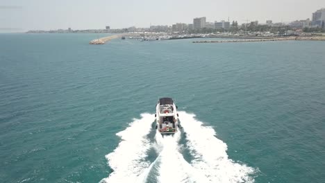 drone tracking shot of white boat speeding fast towards larnaca marina, cyprus