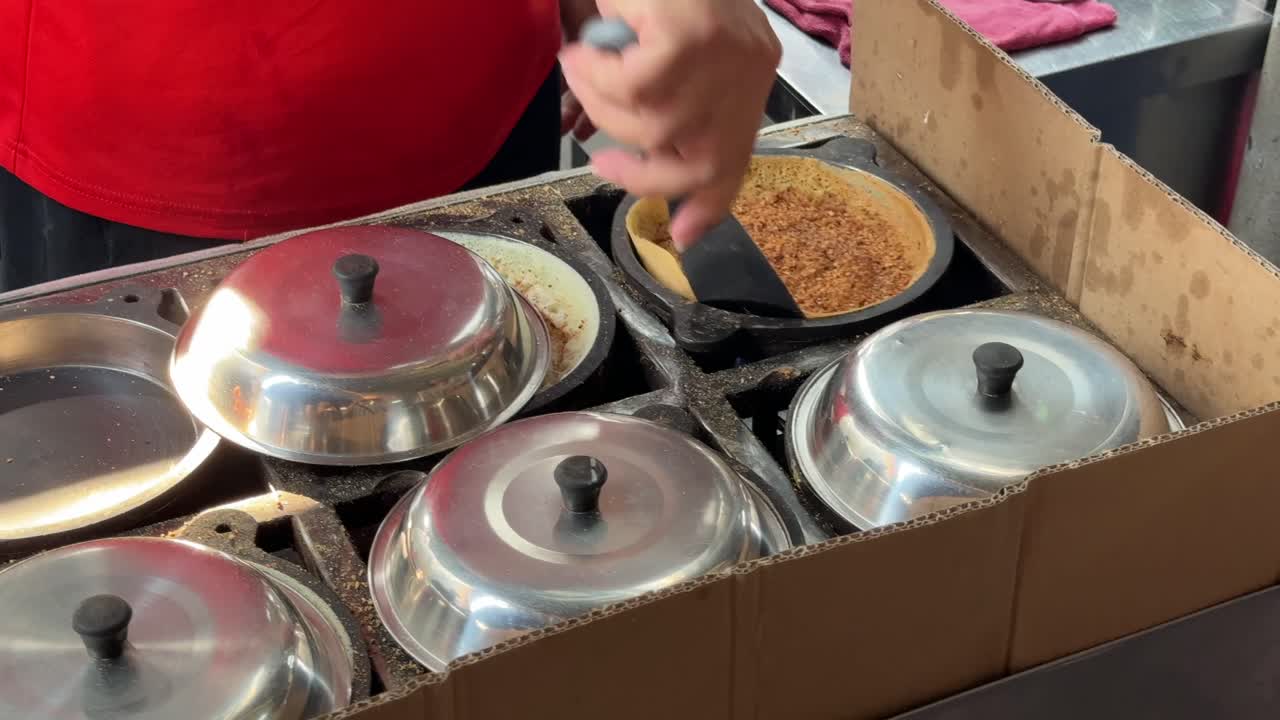 A close-up of a vendor making peanut pancakes, aka apam balik, min jiang kueh or tai kau min on a hawker street food stall in Penang, Malaysia
