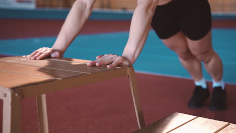 deportista rubia enfocada calentando y haciendo ejercicio de estiramiento en una instalación deportiva cubierta