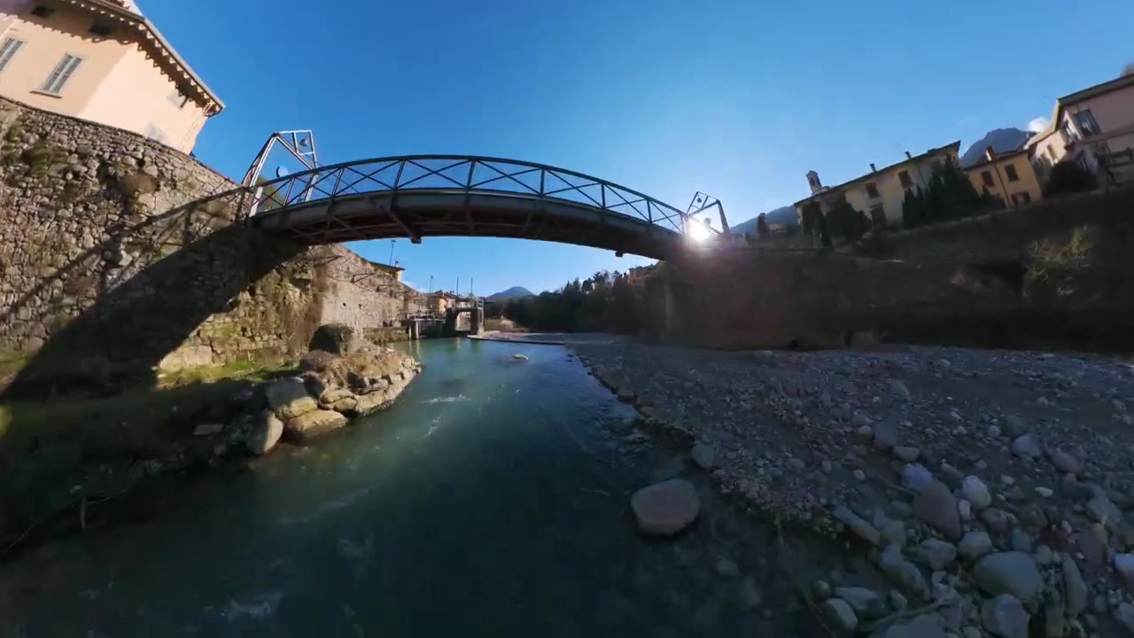 Dron volando bajo un puente de arco de piedra que cruza un río poco profundo cerca del Lago Endine, Italia. Avance aéreo.