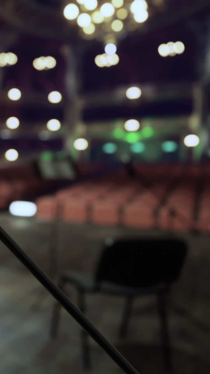 View of an empty theater stage with chairs and lights in the background