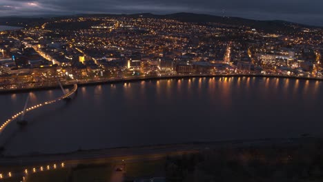 aerial night view of a city with a bridge and river