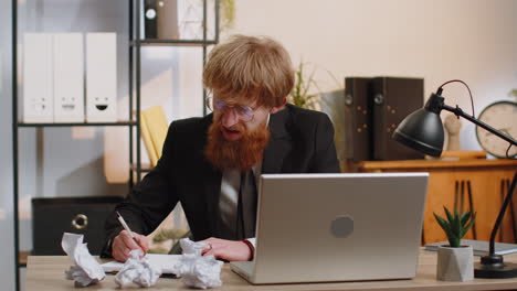 angry furious man working at home office throwing crumpled paper, having nervous breakdown at work