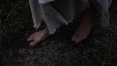 closeup of robed mans feet or jesus walking through forest trees