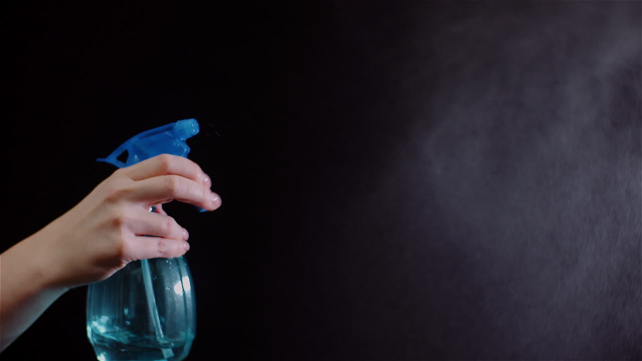 스프링클러를 사용하여 손을 닫고 검정색 배경에 물을 뿌린다 1