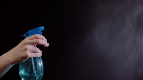 primer plano de la mano usando rociadores y rociando agua sobre fondo negro 1