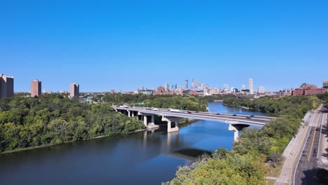 reveal through the green trees the minneapolis skyline in the summer just over the river and the hiawatha highway and bridges