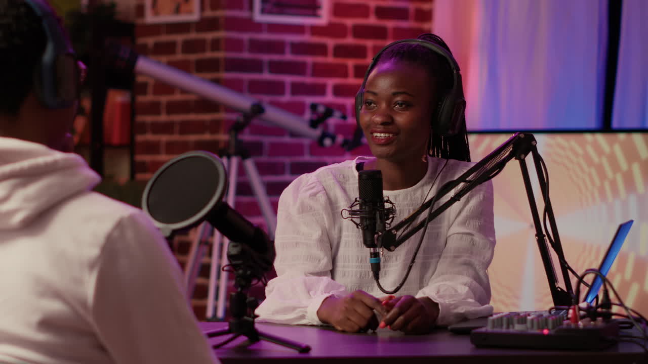 Closeup of african american podcast host interviewing male influencer for online broadcast using professional microphones