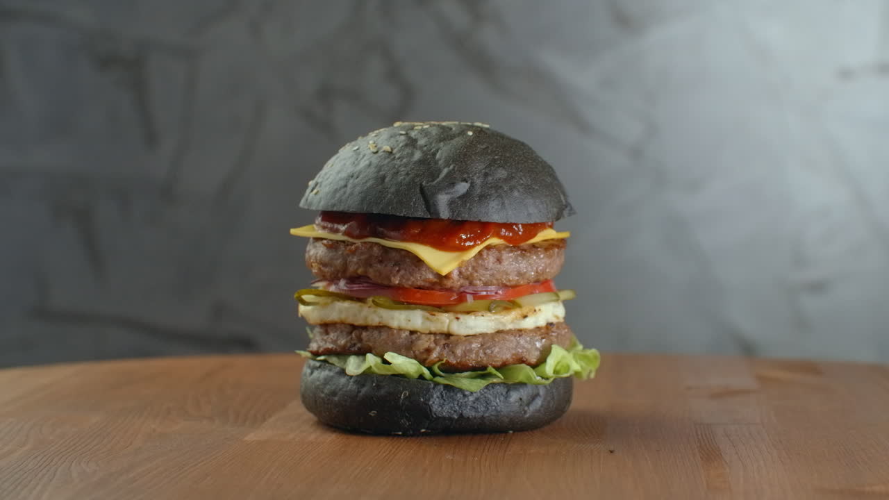 hamburguesa negra de pavo con setas y salsa de setas en una bandeja de piedra negra