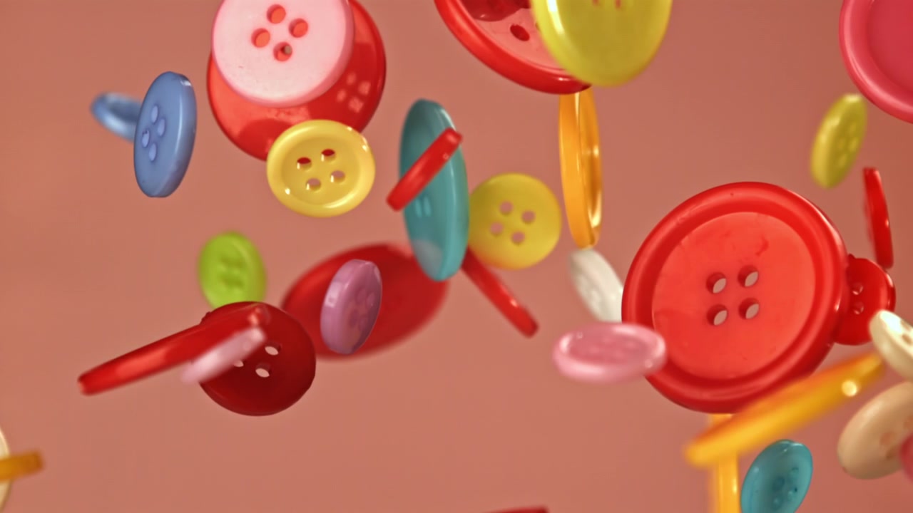 Bottoni da cucito colorati che fluttuano e cadono al rallentatore.