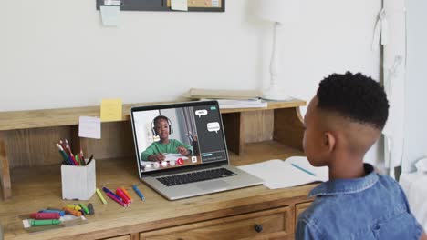 escolar usando una lección en línea de computadora portátil, levantando la mano, con escolar y chat web en la pantalla