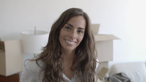 happy long-haired hair woman standing in the living room of her new house and posing for the camera