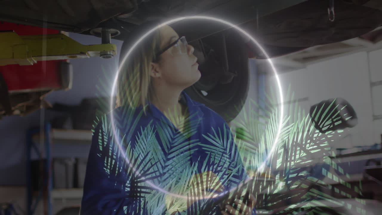 Female auto technician inspecting undercarriage beneath lift, showing neon ring and leaf overlays