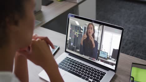 Mid-section-of-african-american-woman-having-a-video-call-with-female-colleague-on-laptop-at-office