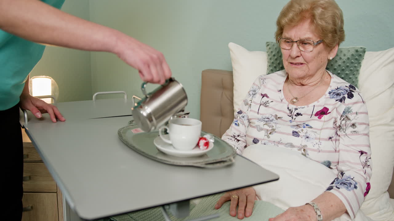 Caregiver Serving Coffee to Elderly Patient in Hospital Bed